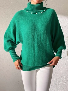 Detail of emerald green high-neck sweater with pearl embellishments on the neckline