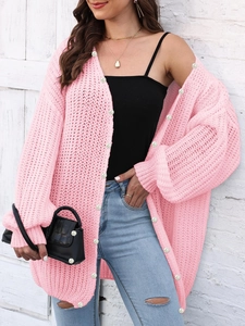 Pink chunky knit cardigan with pearl buttons worn over a black top and jeans