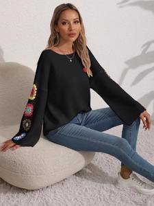 Close-up of colorful crocheted floral patches on black knit sleeves with detailed texture