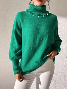 Detail of green turtleneck sweater showing elegant white pearl trim on the neckline