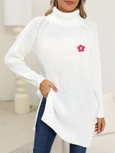Detailed view of white turtleneck sweater with a pink knit flower and side slits