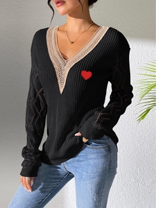 Détail de pull en tricot à col en V avec dentelle marron et broderie coeur rouge