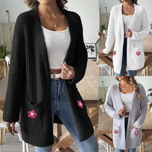Détail du cardigan en maille avec poches plaquées et applique fleurie rose au crochet