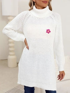 Detail of white chunky knit turtleneck sweater featuring a pink crochet flower applique