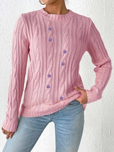 Detail of pink knitted sweater showing cable knit patterns and purple floral embroidery