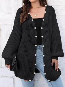 Detail of loose knit cardigan featuring elegant white pearl bead trim and soft texture