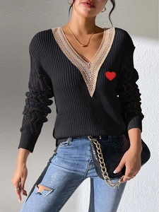 Détail d'un pull en tricot noir pour femme avec col en V en dentelle et écusson cœur