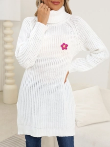Close-up of knit dress featuring hand-crocheted pink flower on a white turtleneck
