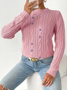 Close-up of pink cable knit sweater with purple floral embroidery and round neckline