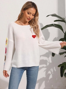 Detail of red heart embroidery and colorful crochet patchwork on white knit sweater