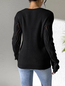 Detail of black pointelle knit sweater featuring diamond hollow-out sleeves and ribbed texture