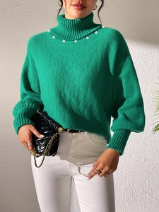 Detail of green turtleneck sweater with elegant pearl embellishments along the neckline
