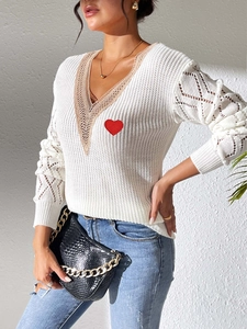 Détail du pull col V avec bordure en dentelle, écusson cœur et manches ajourées