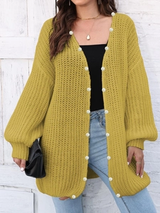 Detail of chunky knit mustard yellow cardigan with elegant pearl buttons for women