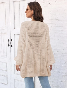 Detail of chunky cable-knit cardigan in beige featuring thick texture and oversized fit