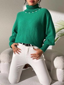 Detail of emerald green turtleneck sweater featuring delicate white pearl collar embellishment