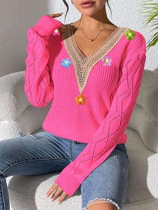 Detail of bright pink knit sweater featuring 3D floral accents and lace V-neckline