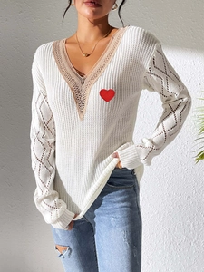 Détail du pull en maille à col en V avec dentelle et broderie coeur rouge sur la poitrine