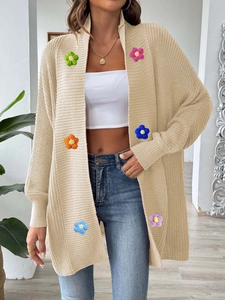 Détails de fleurs au crochet 3D colorées sur un cardigan beige en maille épaisse à côtes