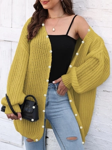 Close-up of vibrant yellow chunky knit cardigan with large white pearl button details