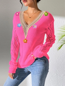 Detail of rose pink V-neck sweater with cream lace trim and colorful knit flower patches