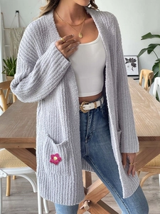 Vue détaillée de la maille duveteuse et de la petite fleur en crochet sur la poche
