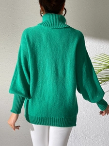 Detail of bright green knit sweater showing ribbed turtleneck and oversized lantern sleeves