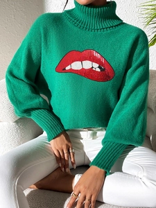 Close-up of green turtleneck sweater with red sequin lip embroidery and knit texture