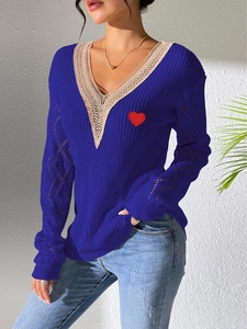 Détail du pull en maille avec col en V en dentelle et broderie coeur rouge sur bleu