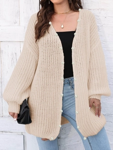 Detail of oversized cream knit cardigan with decorative white pearl buttons on the sleeves