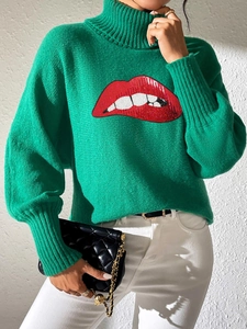 Close-up of green high-neck sweater featuring red sequined lip embroidery and knit texture