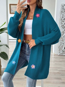 Détail du cardigan en grosse maille sarcelle avec appliques de fleurs crochetées à la main