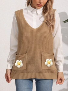 Detail of camel knit vest featuring V-neck and pockets with 3D white knitted flowers