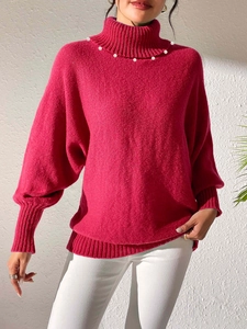 Detail shot of elegant mock neck knit sweater featuring white pearl embellishments
