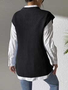 Detail of black knit vest with side slit paired with white shirt and jeans