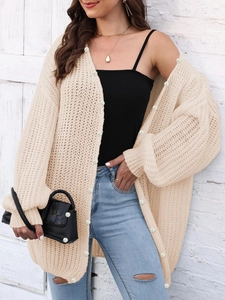Close-up of chunky knit cream cardigan featuring elegant white pearl button details