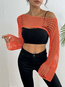 Detail of bright orange crochet shrug featuring loose knit texture and bell sleeves