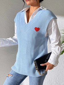 Detalle de bordado de corazón rojo en chaleco de punto azul claro con cuello en V