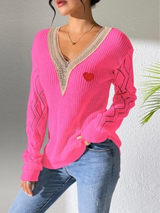 Vue détaillée du pull rose col V avec dentelle beige et écusson de cœur rouge