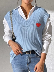 Primer plano del chaleco de punto azul cielo con cuello en V y detalle de corazón bordado