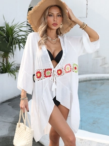 Détail du patchwork au crochet coloré et cordon à gland sur un cache-maillot blanc