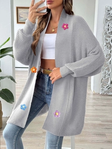 Vue détaillée des appliques florales 3D colorées sur un cardigan gris en maille