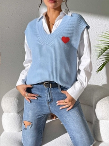 Detalle del chaleco de punto azul claro con cuello en V y bordado de corazón rojo suave