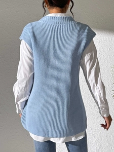 Vista trasera de un chaleco de punto azul claro con texturas verticales y camisa blanca