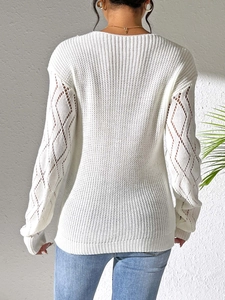 Detailed back view of white knit sweater with hollow-out diamond patterns on long sleeves