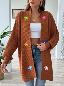 Détail d'un cardigan en maille caramel avec des fleurs en crochet 3D faites à la main
