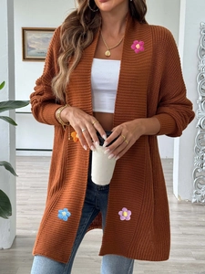 Détail d'appliqués de fleurs au crochet colorées sur un cardigan en maille épaisse