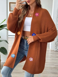 Détail d'un cardigan marron rouille avec appliques de fleurs colorées crochetées à la main
