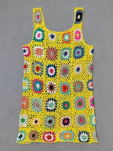 Dettaglio di un vestito da spiaggia giallo all'uncinetto con motivi floreali a maglia