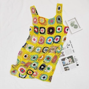 Dettaglio di un abito da spiaggia boho giallo all'uncinetto con fiori colorati a maglia